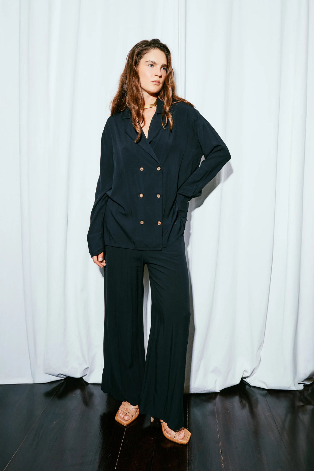 Woman wearing a black suit against a white curtain background