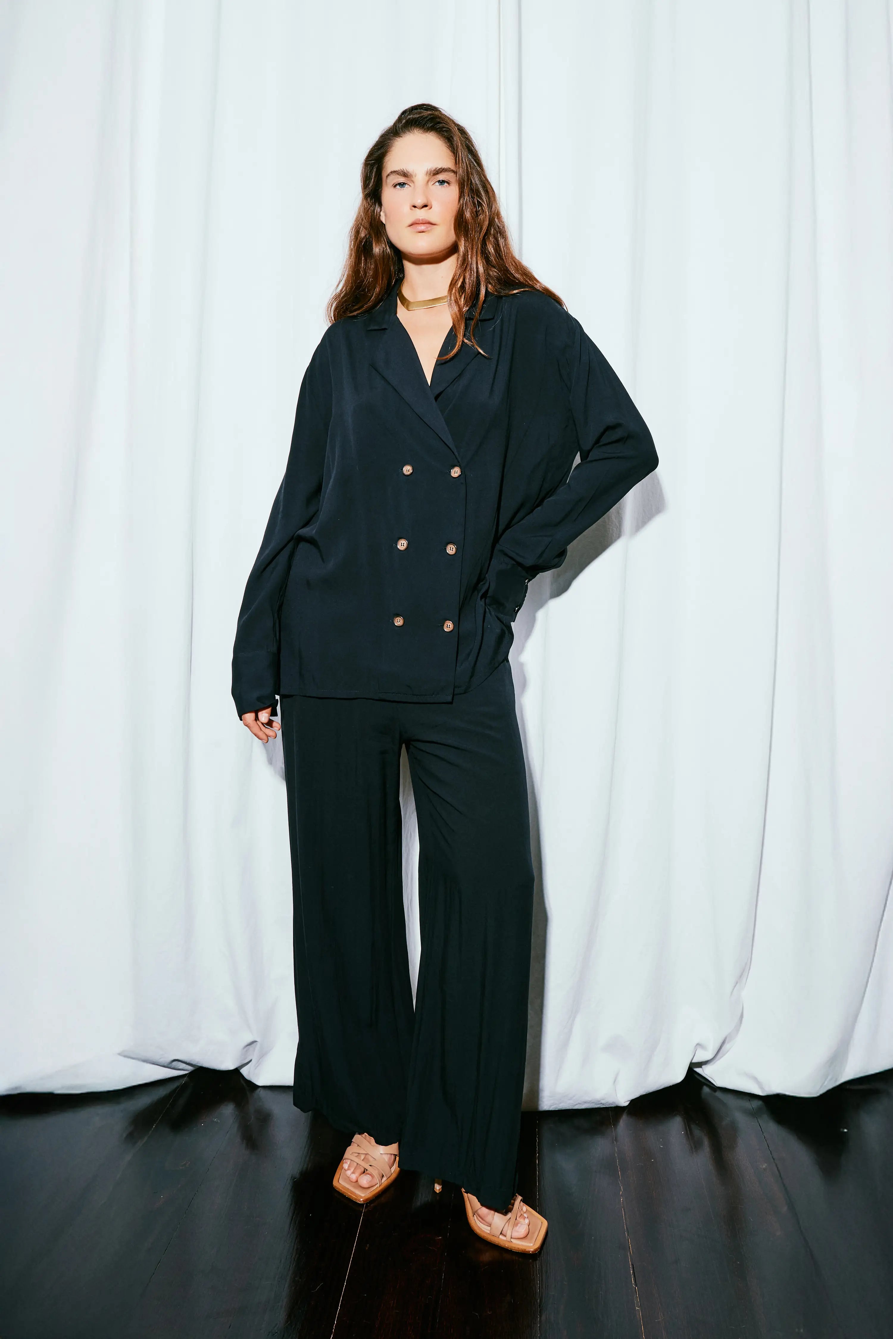 Person wearing a dark suit standing against a white curtain background