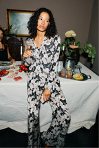 Woman holding a glass of wine at a dinner table with food and drinks.