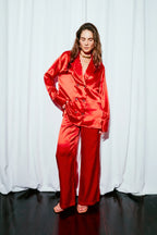 Woman wearing a red silk suit against a white curtain background